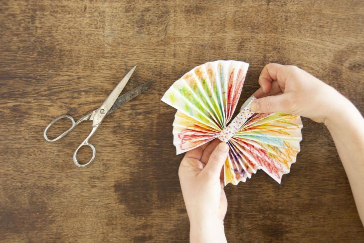 Jemand umwickelt die Kontaktstelle zwischen zwei Papierfächern mit Maskingtape.