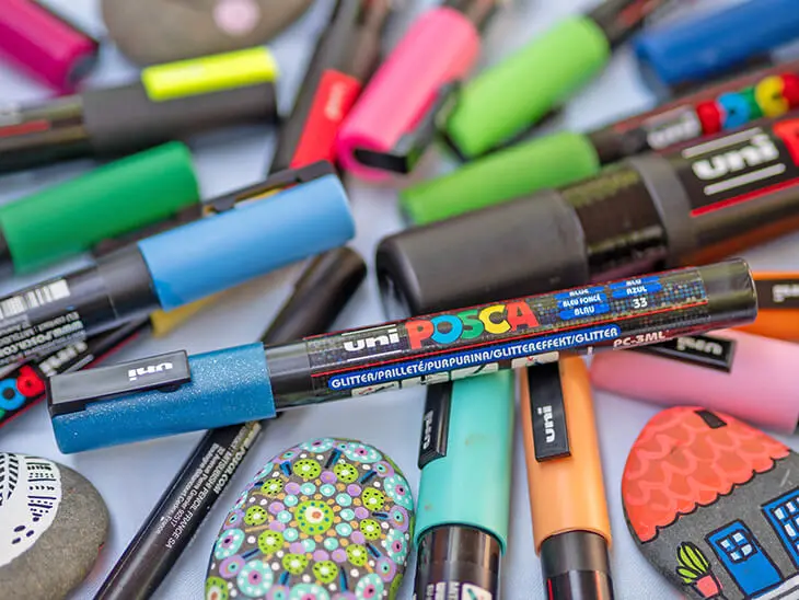 Viele verschiedene POSCA-Marker liegen verstreut auf einem Tisch. Foto: Johanna Rundel