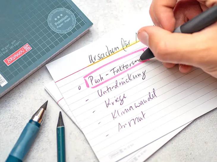 Jemand schreibt Informationen auf eine Karteikarte von BRUNNEN. Foto: Johanna Rundel