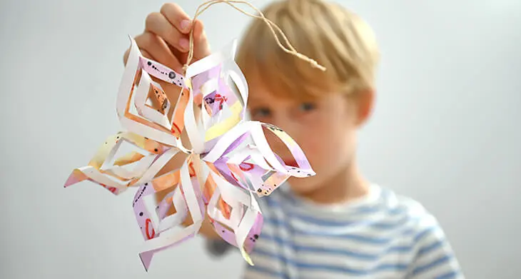 Ein Kind hält einen selbstgebastelten Stern aus Papier in die Kamera. Foto: Johanna Rundel