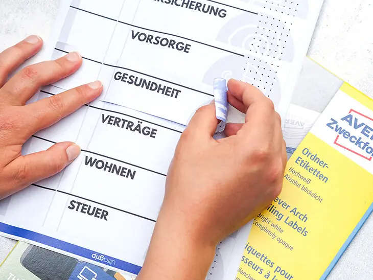 Jemand zieht ein Avery Zweckform Orderrücken-Etikett von einem Etikettenbogen ab. Foto: Johanna Rundel