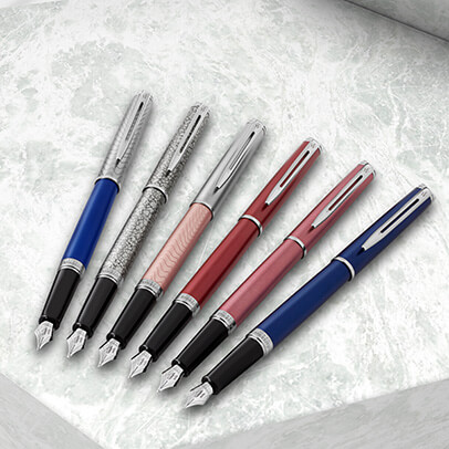 Sechs Füller der Marke Waterman auf einem marmorierten Untergrund.