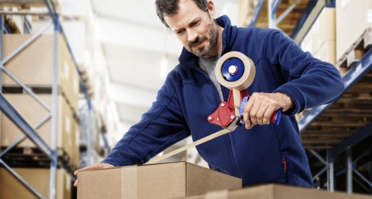 Ein Mann packt ein Paket mit dem tesa® Packband ein.