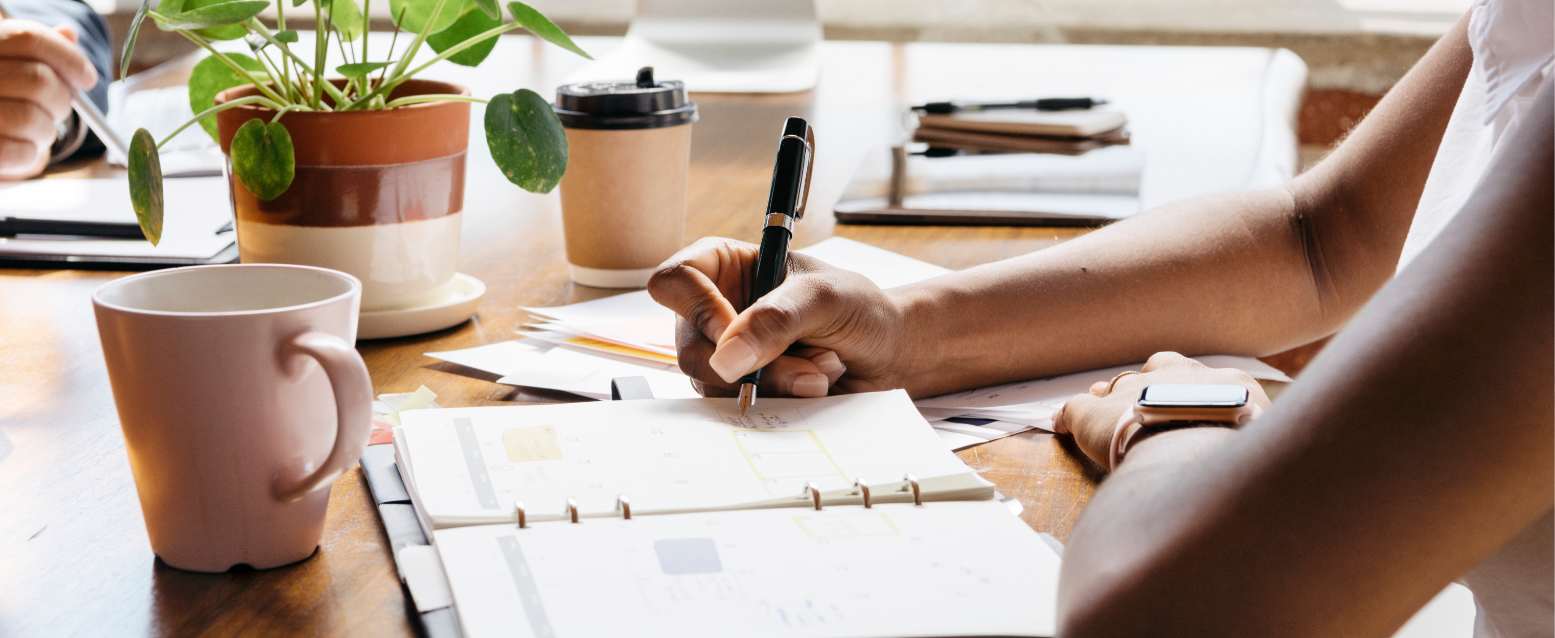 Ein Aufnahme eines Schreibtisches, eine Person trägt etwas in einen Kalender ein.