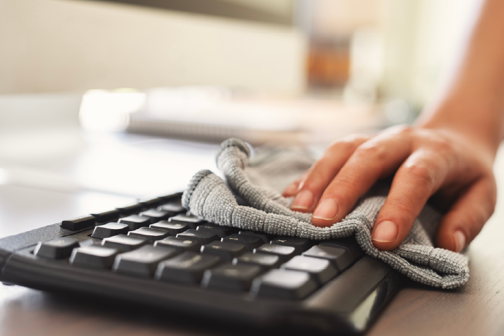 Eine Computertastatur wird mit einem Tuch abgeputzt.