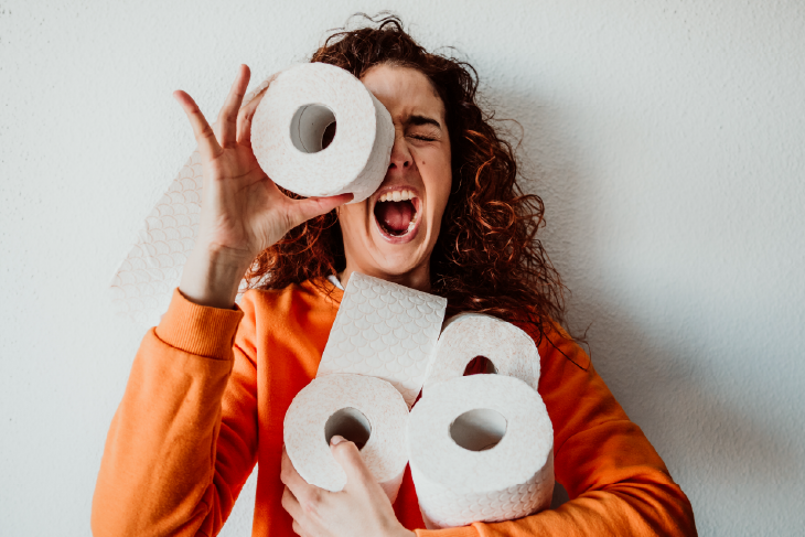 Eine Frau mit vielen Rollen Toilettenpapier in den Armen.