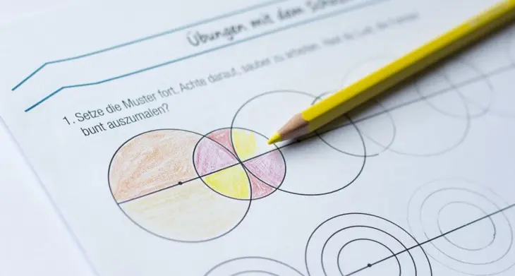 Auf einem Arbeitsblatt sind Zirkelübungen zu sehen, die mit Buntstiften ausgemalt wurden.