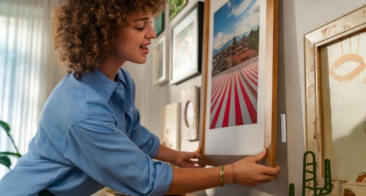 Eine Frau hängt ein Bild an die Wand.