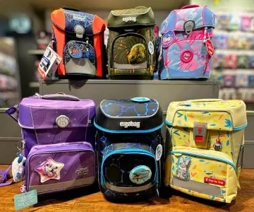 Schulranzen von ergobag und Step By Step vor einem Regal