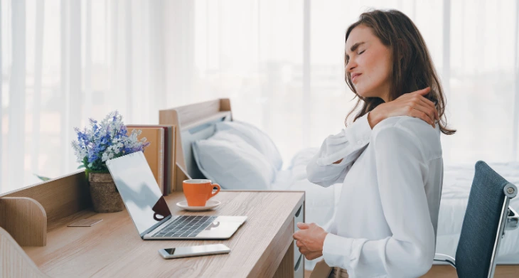 Frau mit Nackenschmerzen am Schreibtisch.