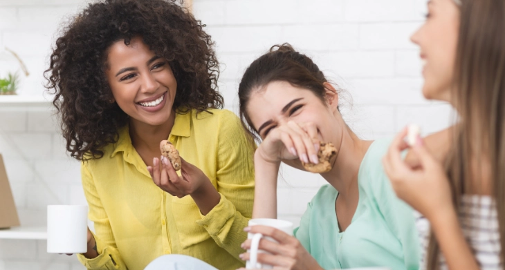 Drei Frauen genießen Kaffee und Kekse in lockerer Runde.
