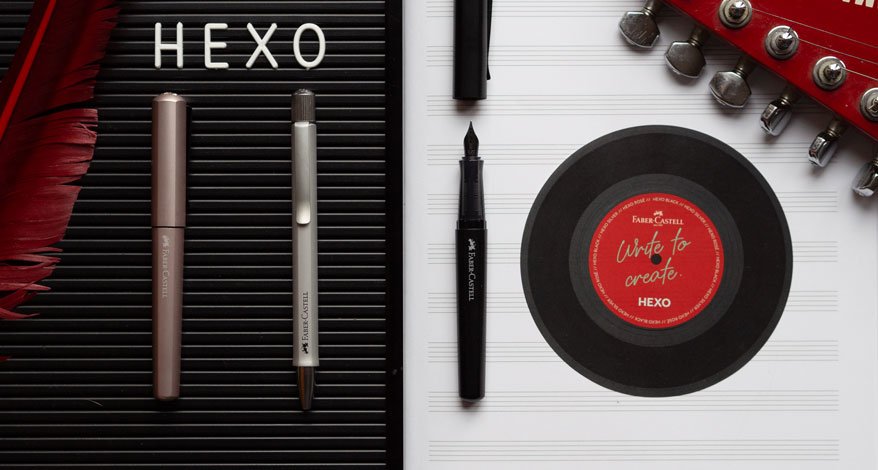 Es sind verschiedene Schreibgeräte der Hexo-Reihe von Faber-Castell zu sehen. Die rechte Seite des Bildes ist schwarz. Eine rote Feder liegt in der Bildecke. Auf der Buchstabentafel, die als Untergrund dient, ist das Wort "HEXO" zu sehen. Die linke Bildseite ist wei. Dort ist eine Schallplatte zu sehen sowie der Griff einer roten Gitarre.