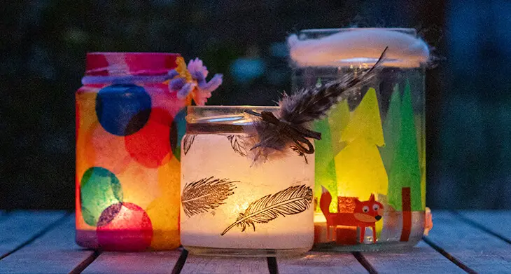 Mit buntem Transparentpapier beklebte Marmeladengläser leuchten als Windlichter