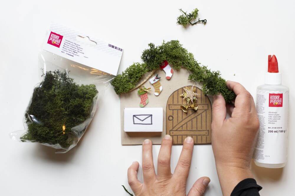 Wichteltür zu Weihnachten basteln, Bastelanleitung Schritt 7: Das Dach des Wichtelhauses mit Hilfe von Flüssigkleber und Islandmoos von Knorr Prandell bekleben.