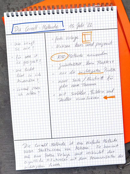 Auf einem dunklen Untergrund liegt ein orangefarbenes Notizbuch, darauf ein karierter Notizblock. Auf dem Block sind Notizen mit der Cornell Methode aufgeschrieben.