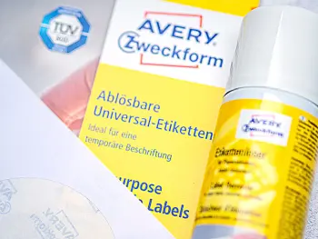 Auf einem hellen Untergrund liegt eine Packung wiederablösbare Etiketten und eine Dose Etikettenlöser von Avery Zweckform. Foto: Johanna Rundel)