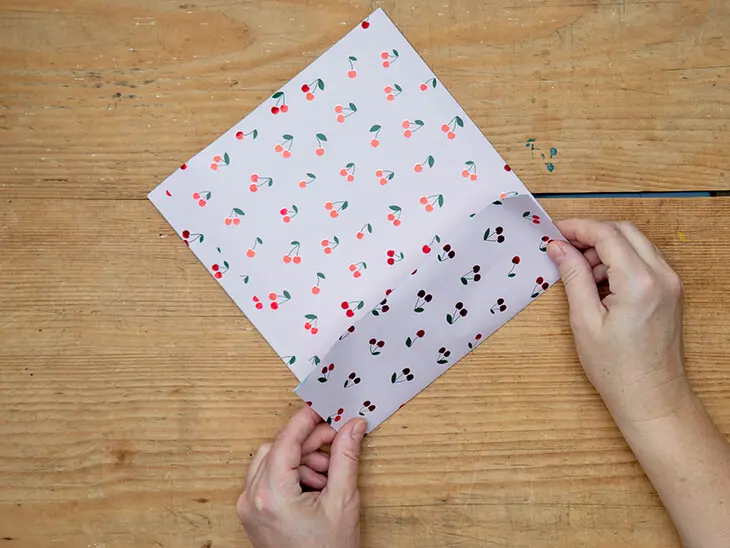 Jemand faltet eine Geschenktüte aus einem Geschenkpapier von STEWO. Foto: Johanna Rundel