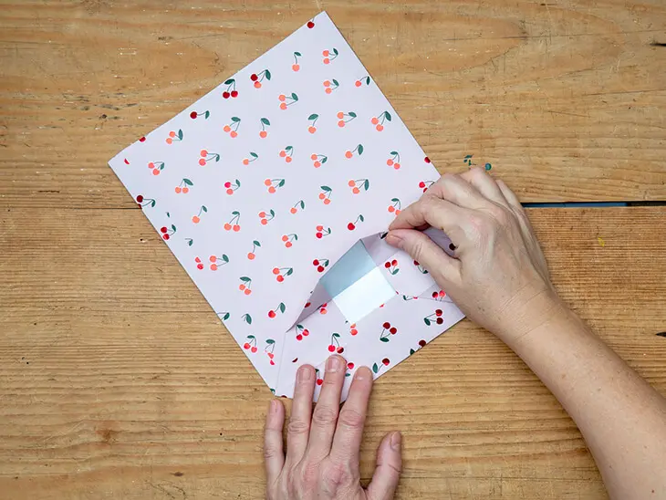 Jemand faltet eine Geschenktüte aus einem Geschenkpapier von STEWO. Foto: Johanna Rundel