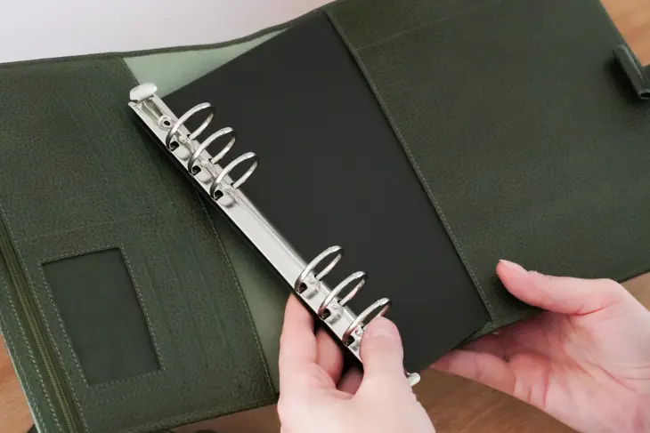 Hände lösen die Ringmechanik aus einem Organizer von Filofax