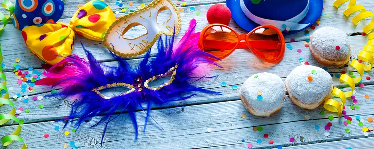 Bunte Karnevalsmasken, Konfetti, Luftschlangen und Berliner liegen auf einem Tisch.
