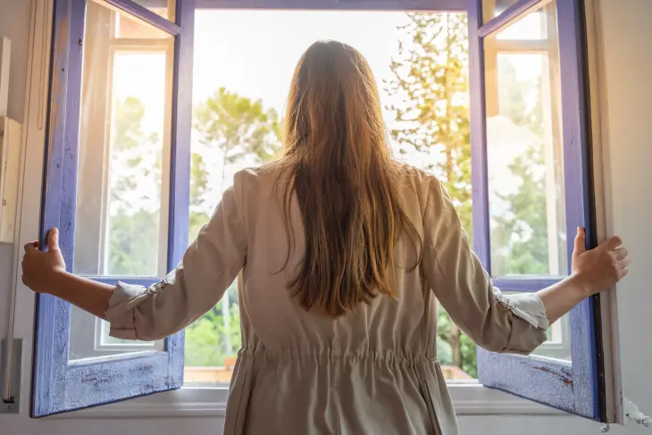 Eine Frau steht vor einem offenen Fenster