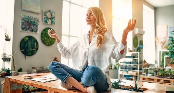 Eine Frau sitzt meditierend auf einem Tisch.