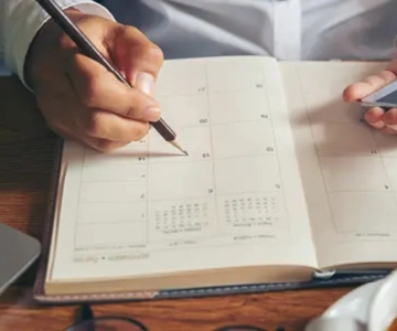 Jemand schreibt in einen Kalender.