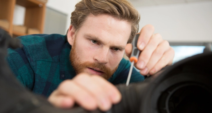 Handwerker mit Schraubendreher bei der Reparatur eines schwarzen Geräts Nahaufnahme seines fokussierten Gesichts.
