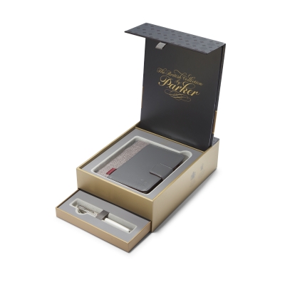 Eine Geschenkschachtel der Marke Parker ist aufgeklappt. Darin liegt ein kleines silbernes Notizbuch, davor liegt eine offene Schatel mit einem Parker Füllhalter.