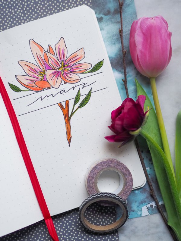 Seite eines Notizbuches mit gelettertem Monat März und Blumen.