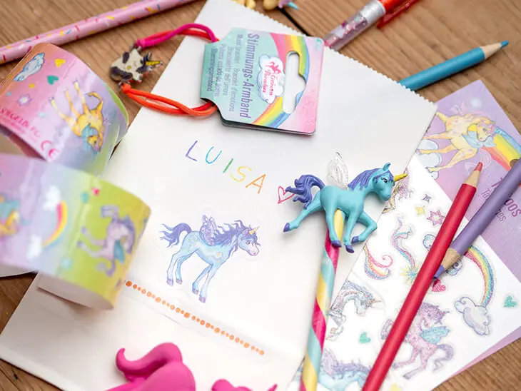 Verschiedene Produkte aus der „Einhorn-Paradies-Serie“ von Die Spiegelburg (Coppenrath Verlag) liegen auf einem Tisch verstreut. Foto: Johanna Rundel