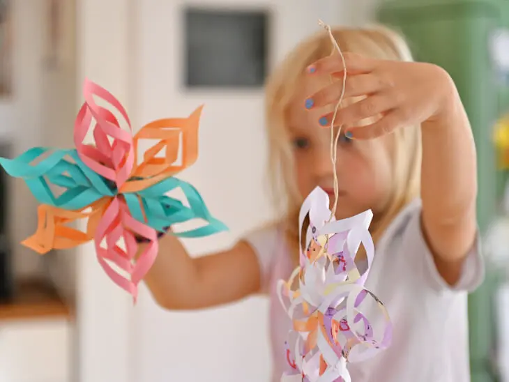 Ein Kind hält zwei selbstgebastelte Sterne aus Papier hoch. Foto: Johanna Rundel