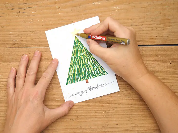Jemand malt mit einem Goldstift von edding einen Stern auf einen Tannenbaum. Foto: Johanna Rundel