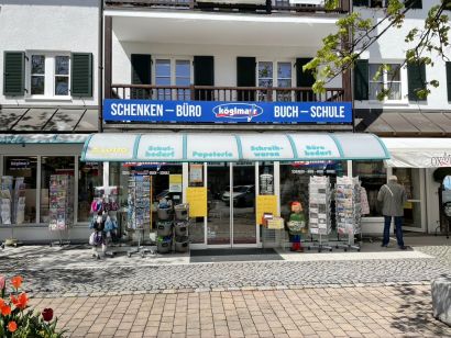 Aussenansicht des Geschäfts Köglmayr in Hersching am Ammersee. Vor den Schaufenstern stehen einige Aufsteller mit Grußkarten.