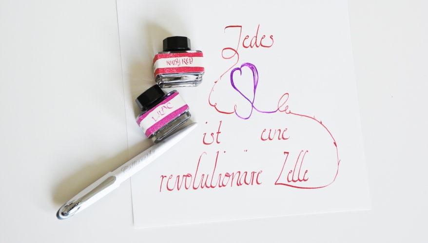 Ein kalligraphierter Text in roter und lila Tinte, geschrieben mit einem Füller.