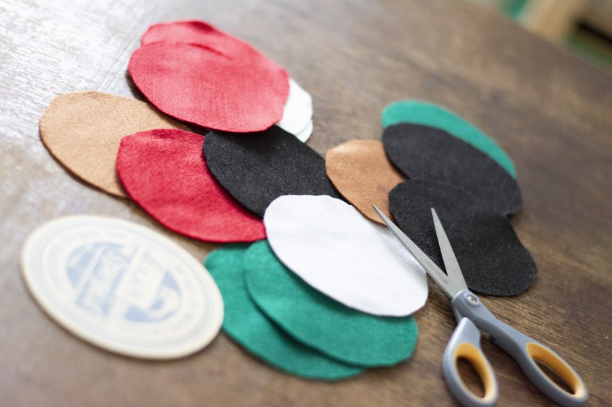 Bunte, runde Filzstücke und Schere auf einem Holztisch
