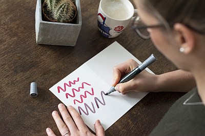 Eine Frau malt wellenförmige Linien auf Schmierpapier