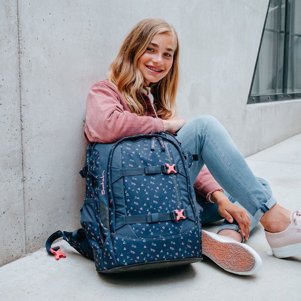 Sitzendes Mädchen mit großem vollem satch-Schulrucksack.
