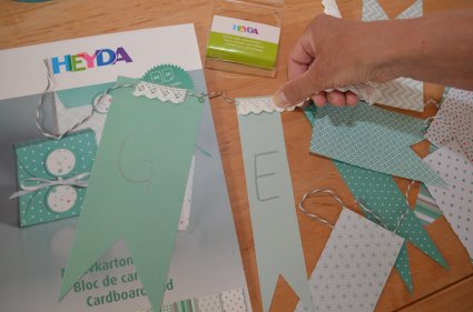 Eine Hand verziert eine DIY-Girlande mit Spitzentape.