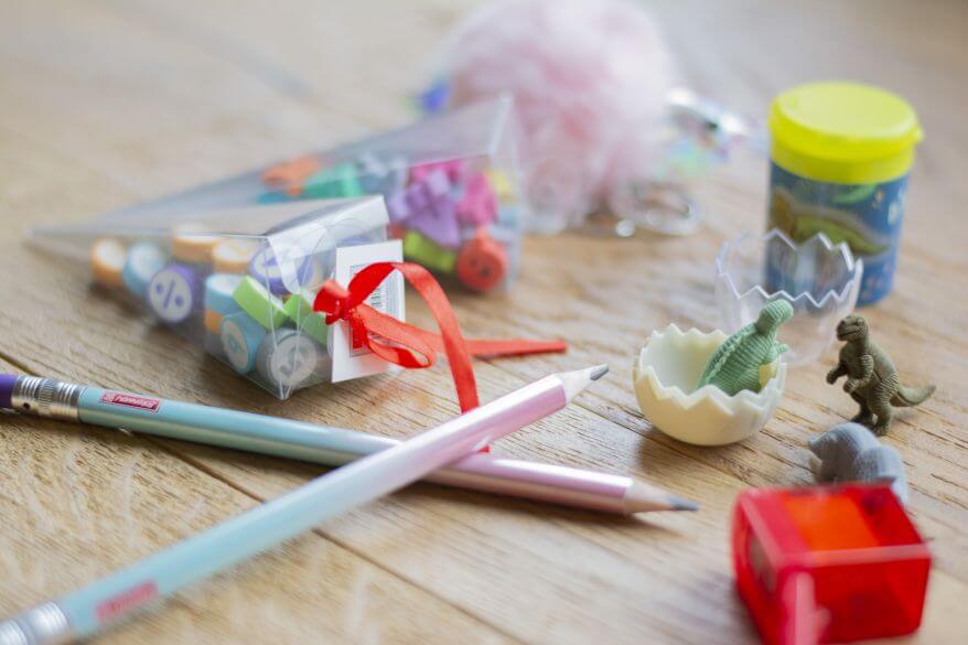 Auf einem Schreibtisch liegen zwei Bleistifte, zwei Anspitzer, Radiergummis in Dinosaurierform.