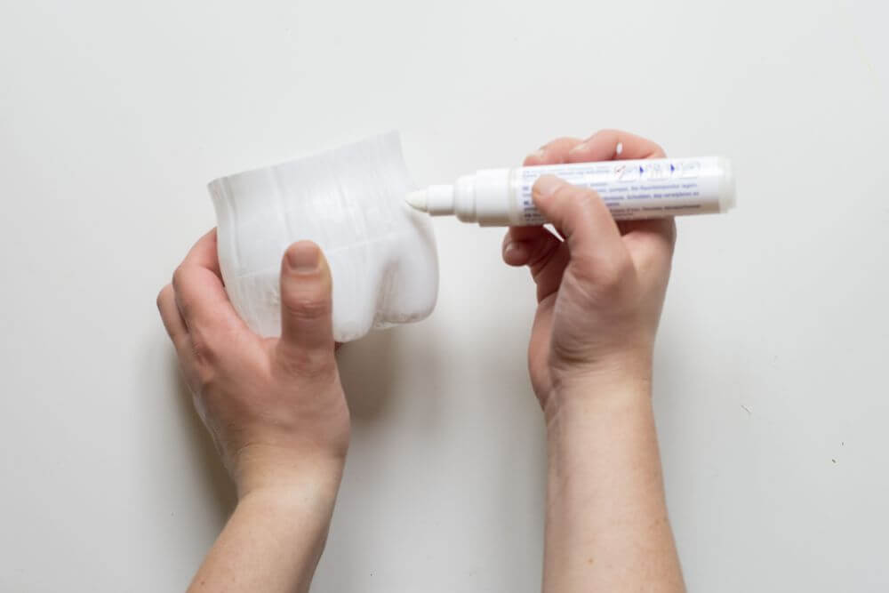 Der Boden einer PET-Flasche wird mit einem weißen edding bemalt.