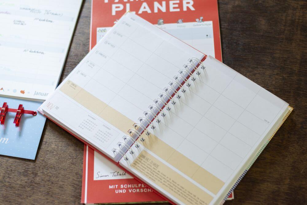Ein aufgeklappter Familienplaner "Mama AG" von Heye liegt als Ringbuchkalender auf einem Tisch.