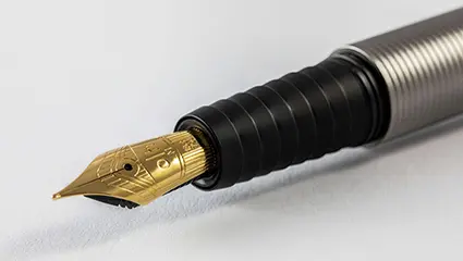 Close-Up eines silbernen Füller mit goldener Feder von Otto Hutt. Der Untergrund ist weiß.