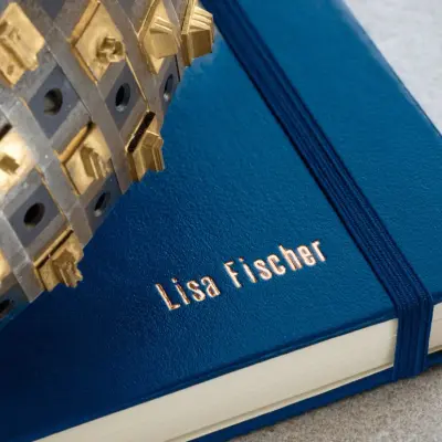 Detailaufnahme eines dunkelblauen Notizbuchs von LEUCHTTURM1917, auf das ein Name in Goldbuchstaben geprägt wurde.