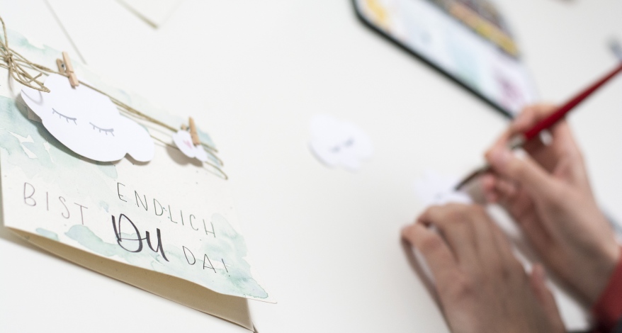 Nahaufnahme einer gebastelten Karte und Hände beim Malen