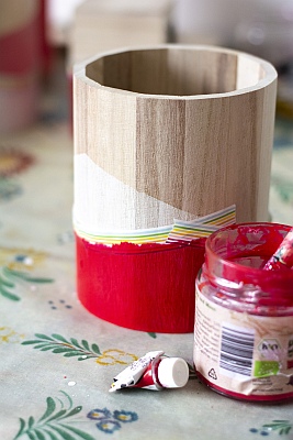 Rote Farbe wird auf bereits bemalte Holzbox aufgetragen