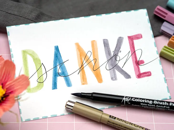 Weiße Postkarte auf die mit Stiften von Sakura „Danke schön“ gelettert wurde. Foto: Johanna Rundel