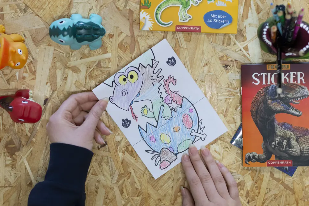 Jemand faltet eine Vorlage für eine Kindergeburtstagseinladung mit dem Drachen Furzipups
