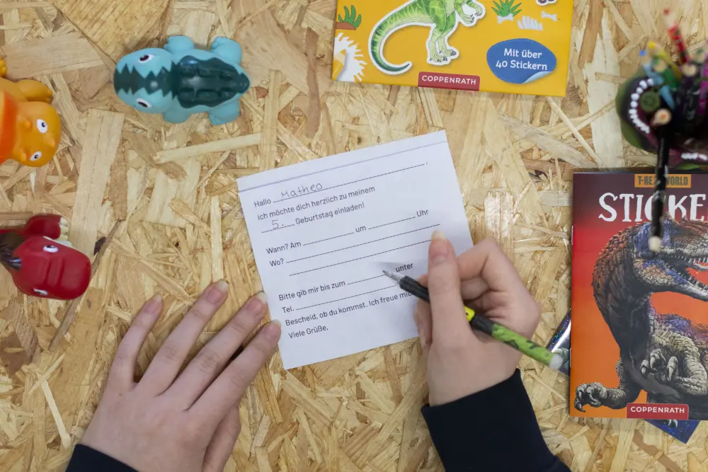 Jemand füllt den Text einer Kindergeburtstagseinladung aus