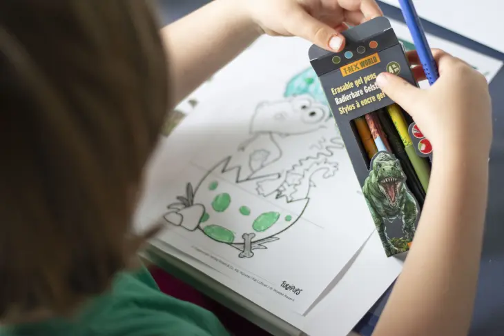 Ein Kind malt mit Gelstiften von Coppenrath eine Kindergeburtstagseinladung mit dem Drachen Furzipups aus